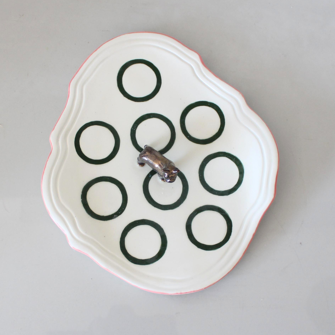 White plate with black circular patterns on a gray background with Frenchie in the middle