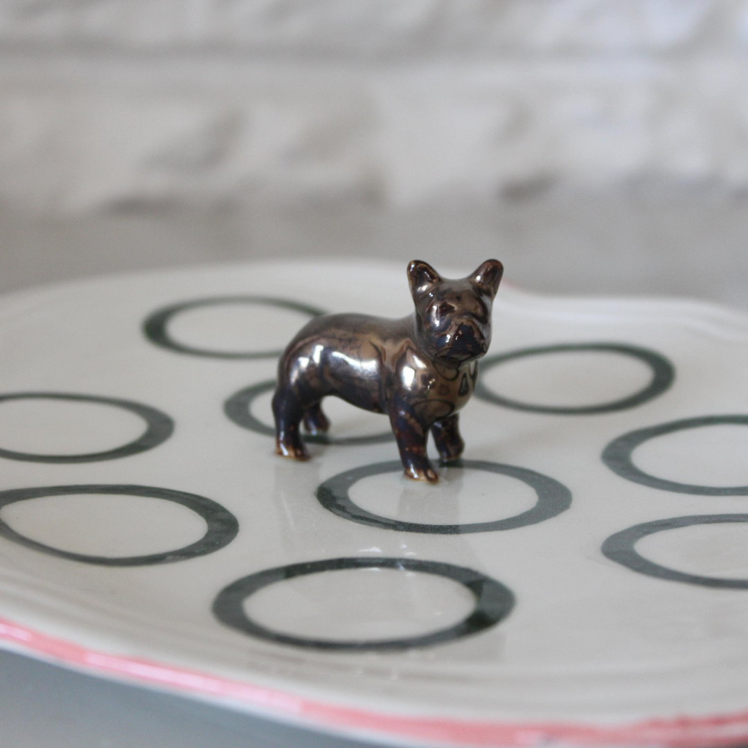 Bronze dog figurine on a ceramic plate with circular patterns
