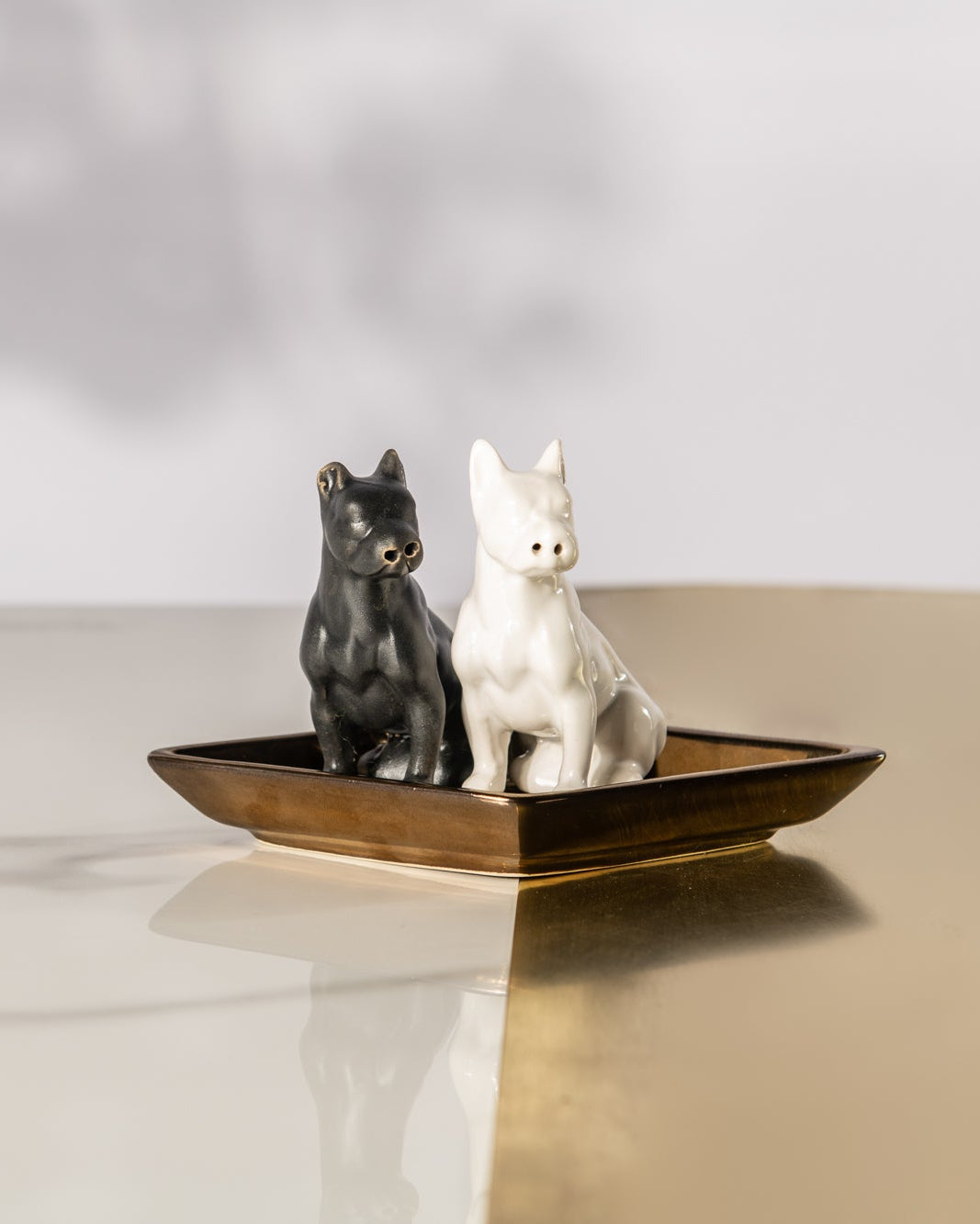 Two small animal figurines on a decorative plate with a neutral background