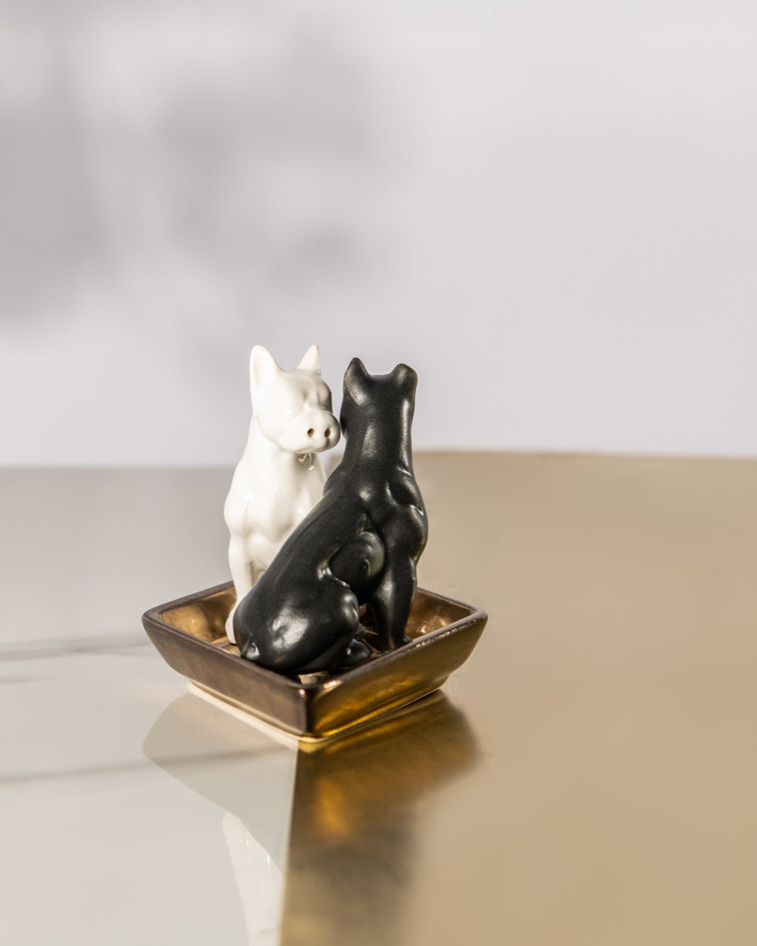 Two ceramic dogs on a small boat with smoke effect on a reflective surface.
