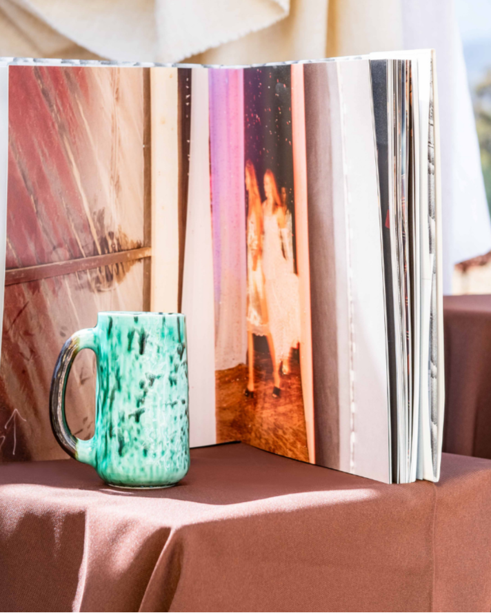 Open photo album with a green mug on a tablecloth