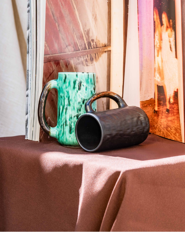Open photo album on a table with handmade ceramic Mugs in a scenic background