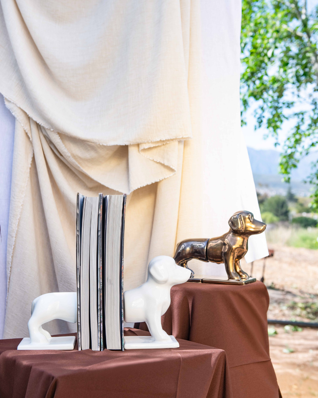 Decorative bookends shaped like a sausage dog on a table with a scenic background