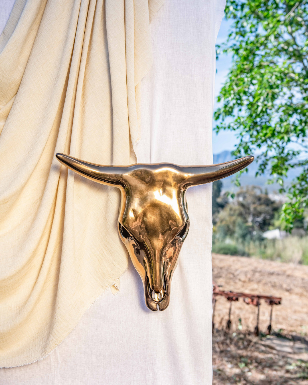 Gold bull head wall decoration against a white curtain with outdoor scenery in the background