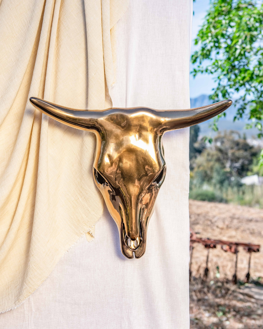 Gold bull head wall decoration against a white curtain with outdoor scenery in the background
