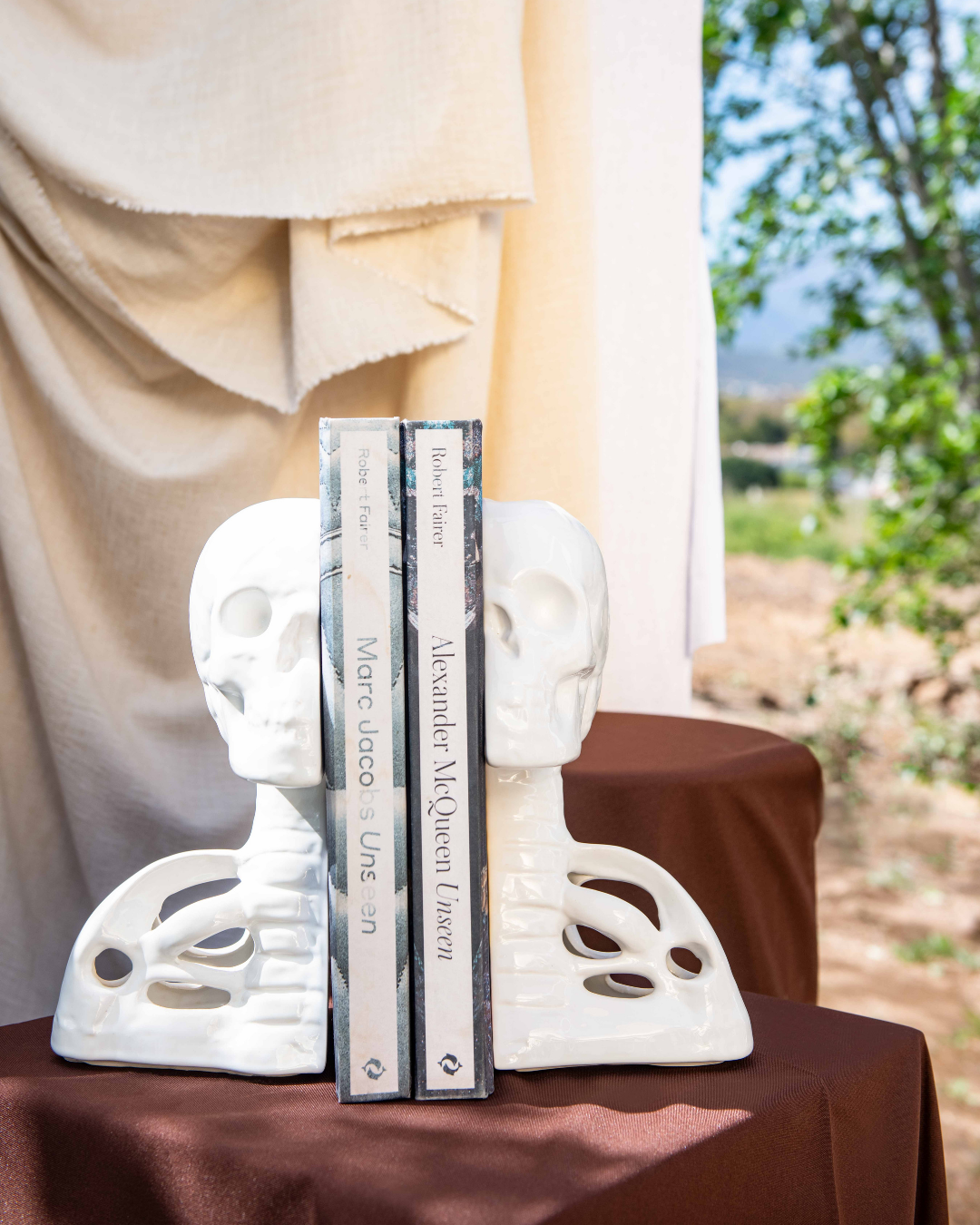 White skull bookends holding books on a table outdoors