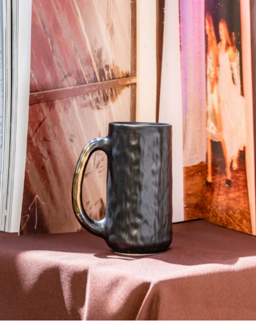 Handmade Mug in matt black on a posium with a scenic back ground