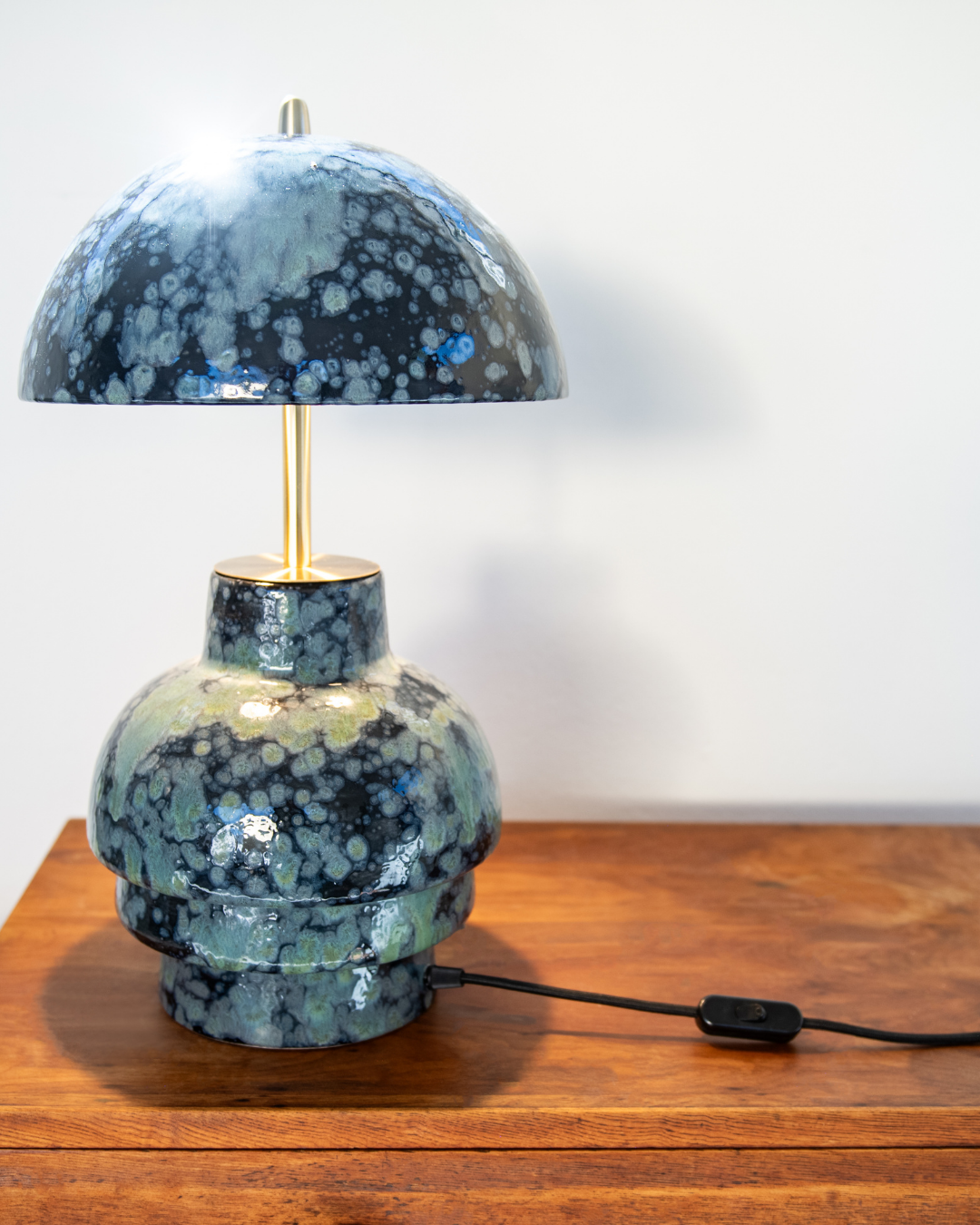 Decorative lamp with a blue and green speckled design on a wooden surface.