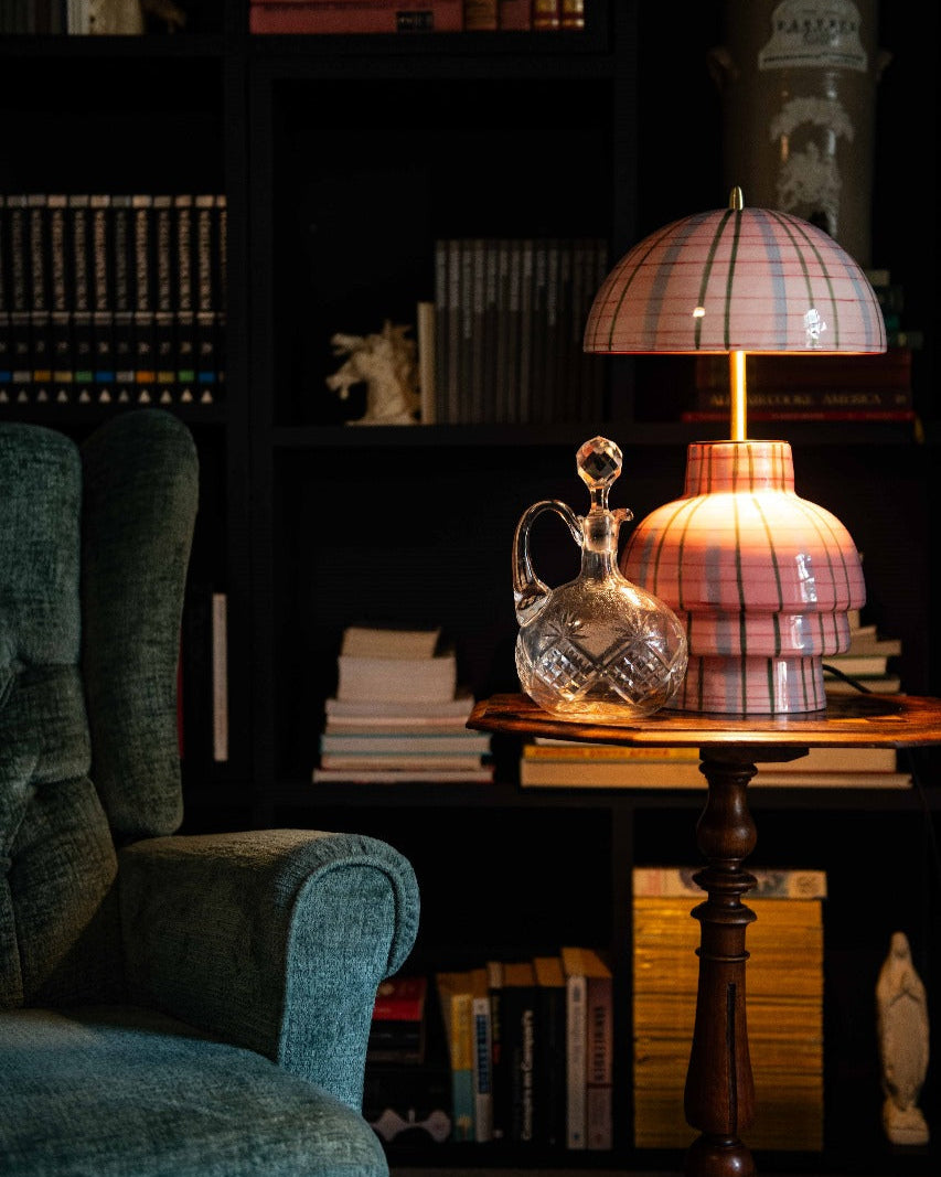 Vintage-style pink check lamp on a wooden table with a bookshelf in the background