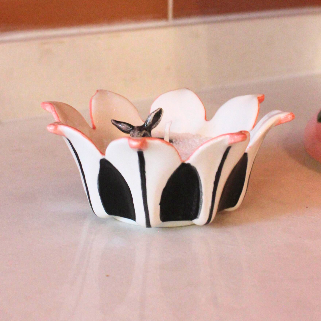 Decorative flower-shaped object with black and white design on a light background Riverine sand wax candle vessel from RIalheim