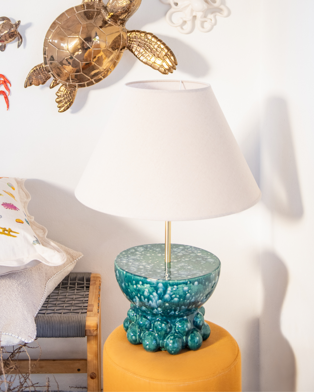 Decorative lamp with a blue base on a yellow surface, with a Bronze turtle sculpture in the background.