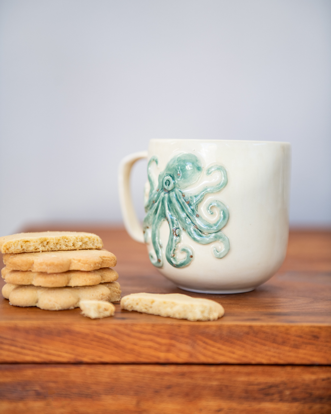 White mug with octopus design on a wooden surface with cookies