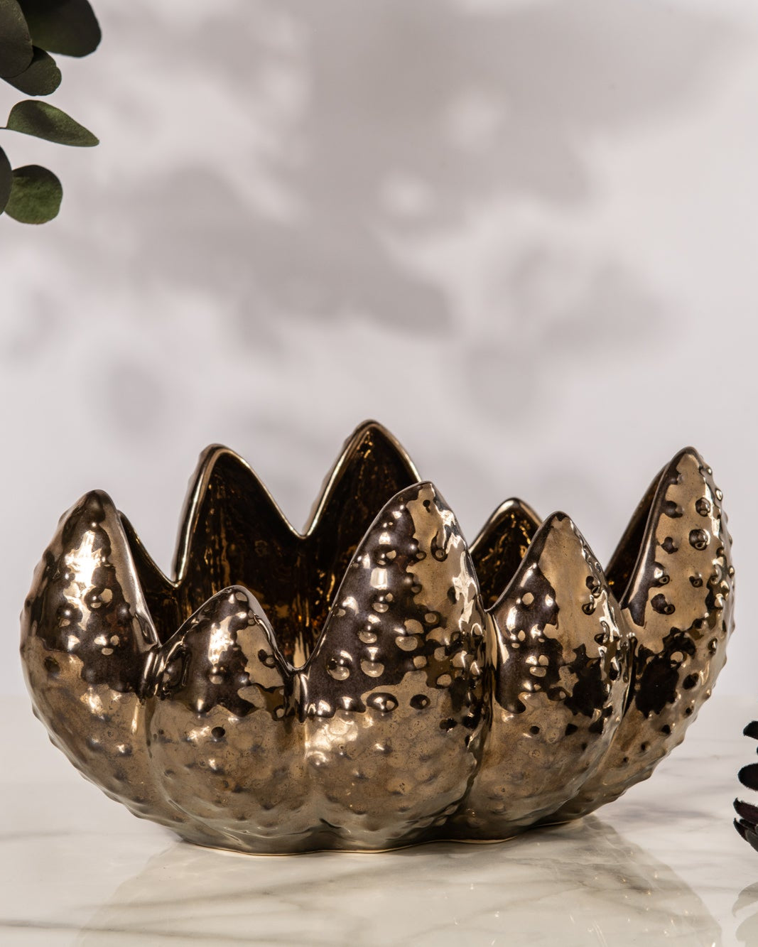 Decorative metallic vase with textured surface on a light background