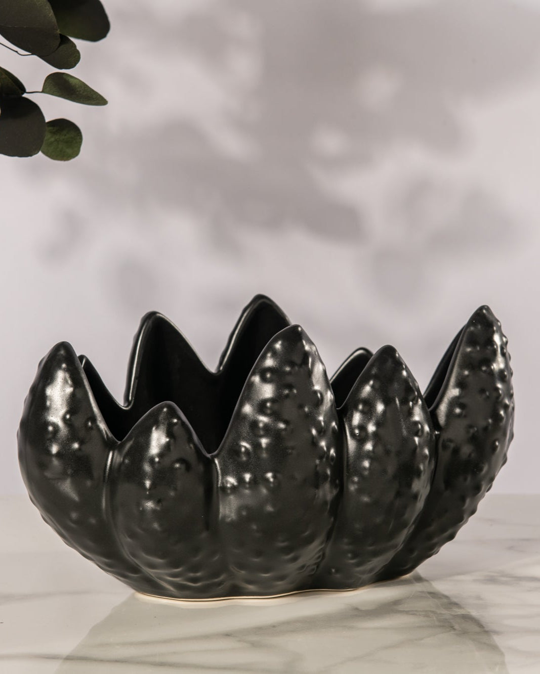 Black ceramic bowl with unique design on a light surface with a blurred background