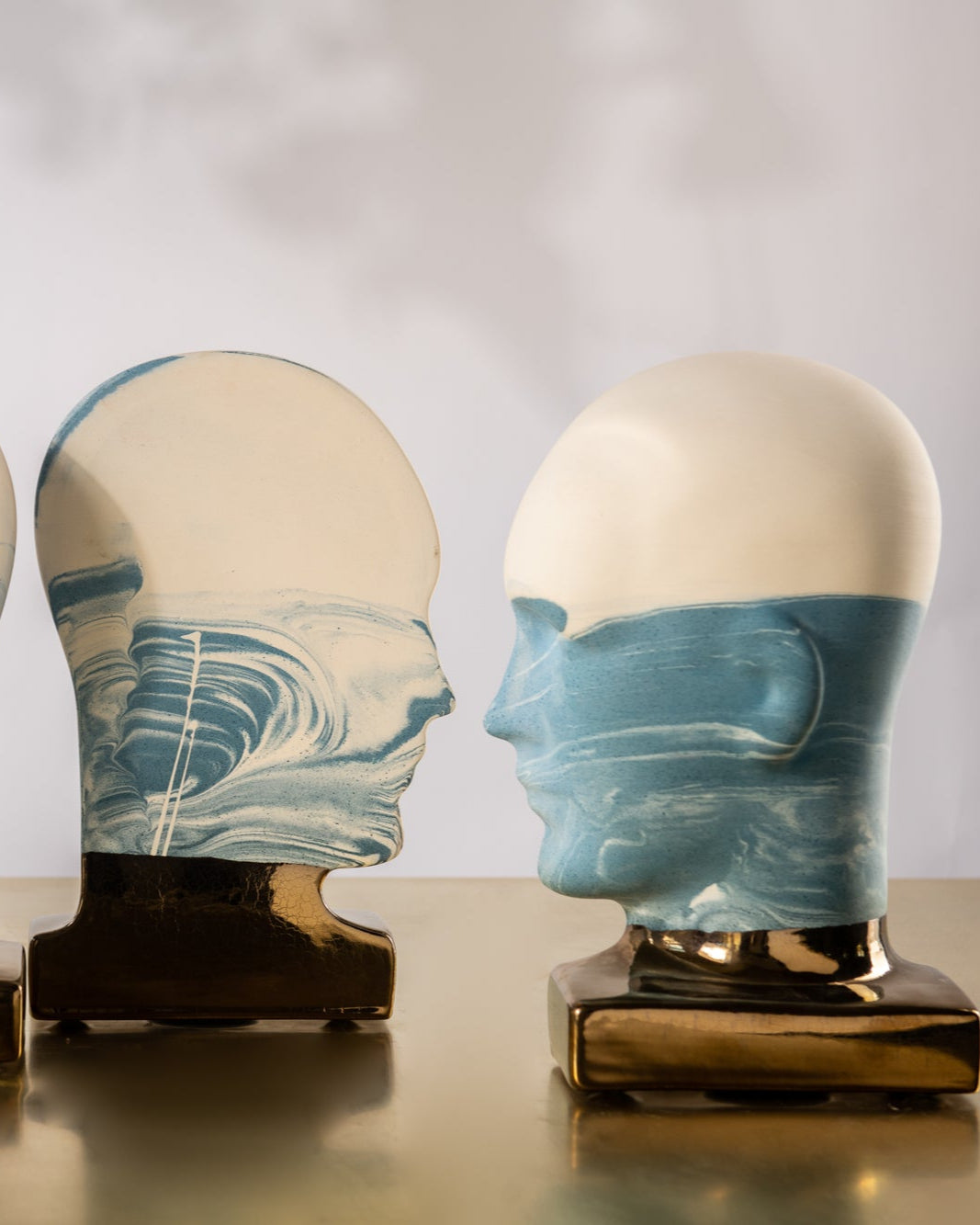 Three decorative heads with marbled blue and beige design on a reflective surface.