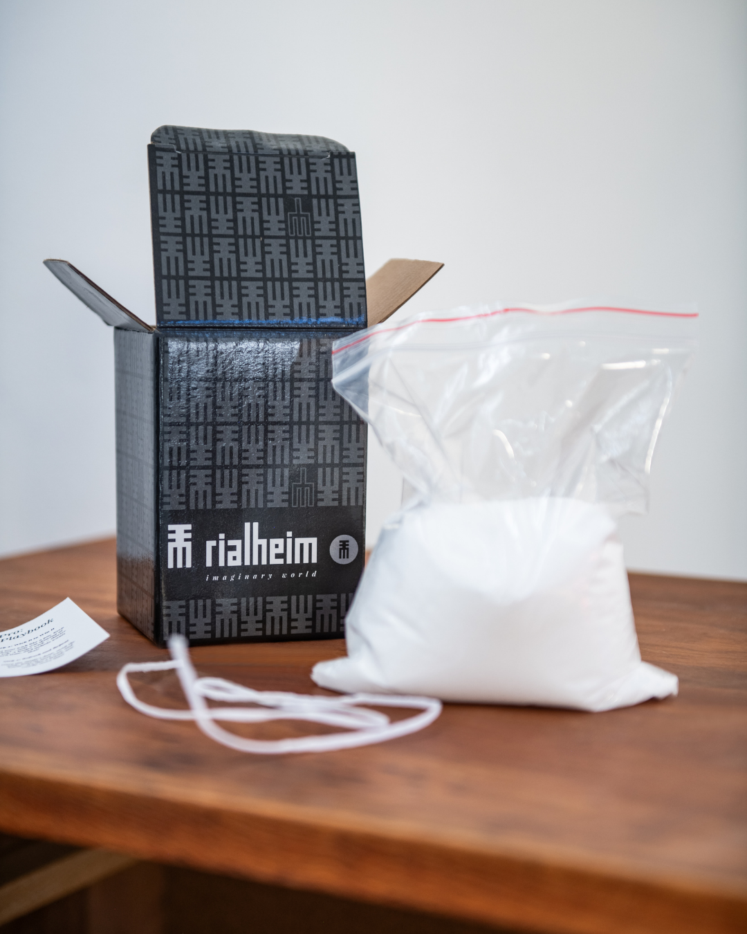 Rialheim product packaging with a clear bag of sandwax and wicks on a wooden surface.