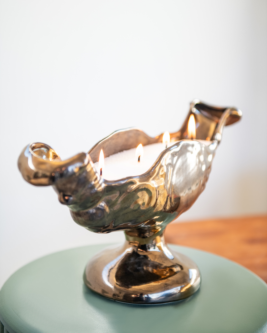 Decorative metallic oil lamp on a light green surface with a blurred background
