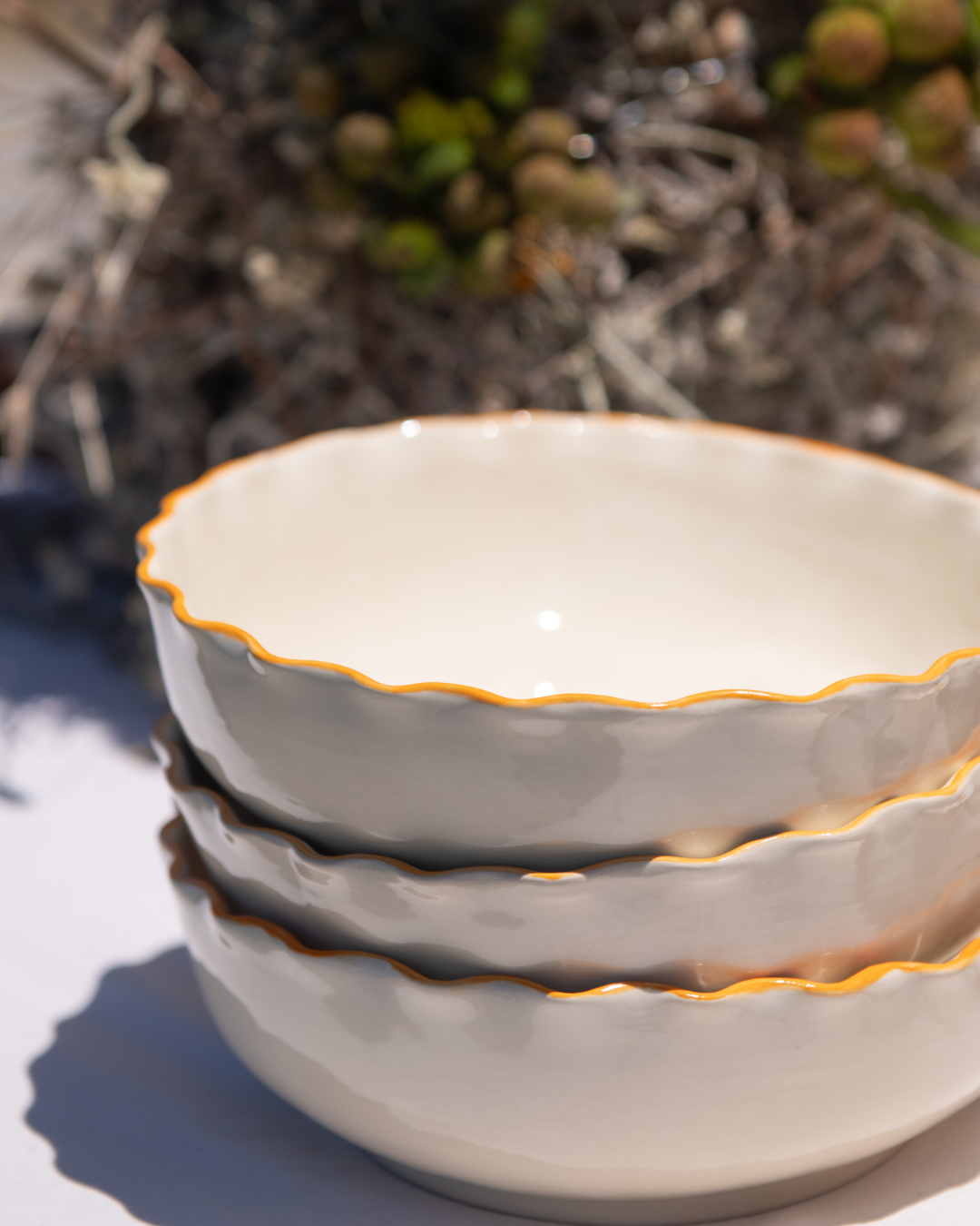 Stack of ceramic bowls with scalloped edges on a natural background