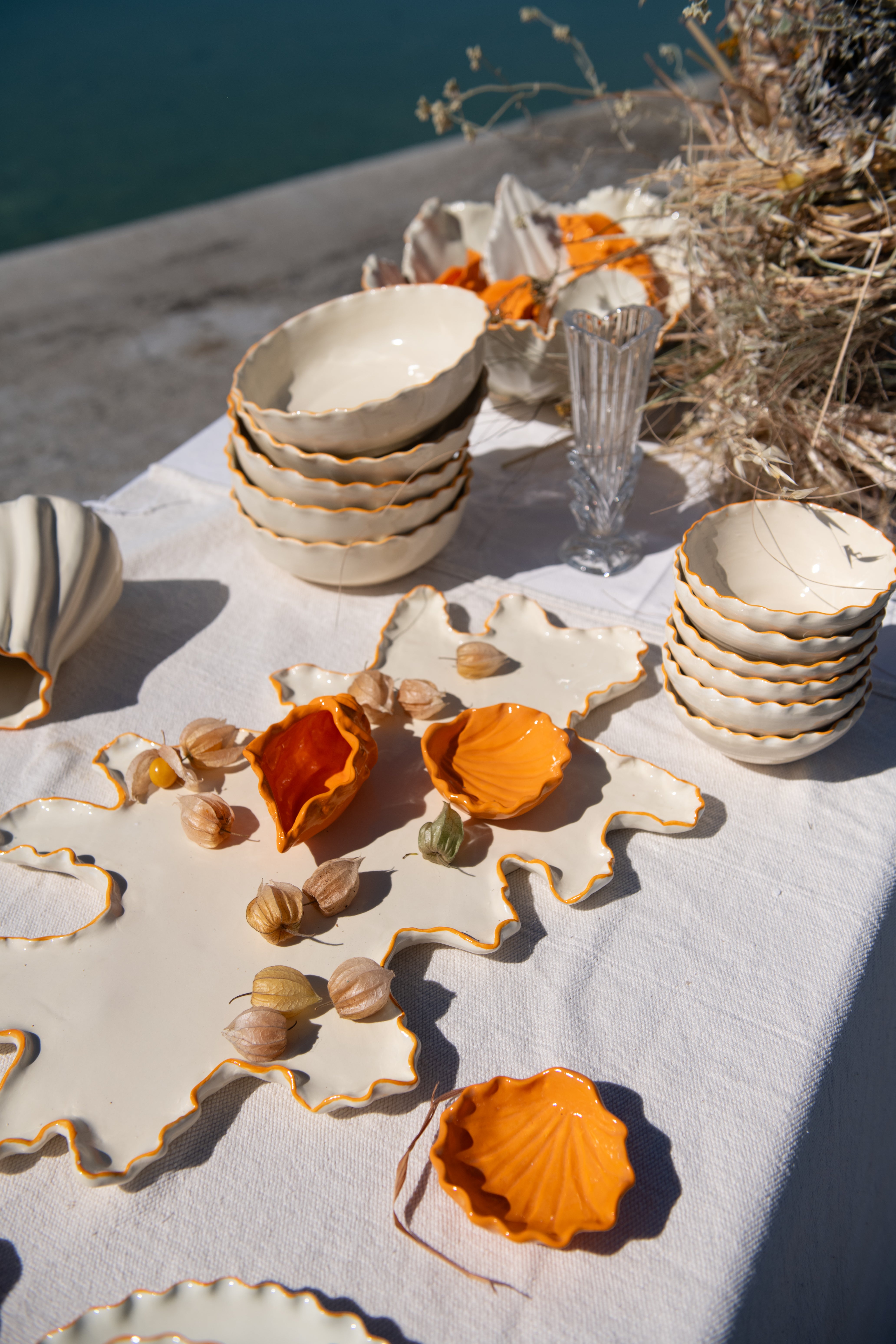 Ceramic plates and bowls on a table with orange flowers and a natural background