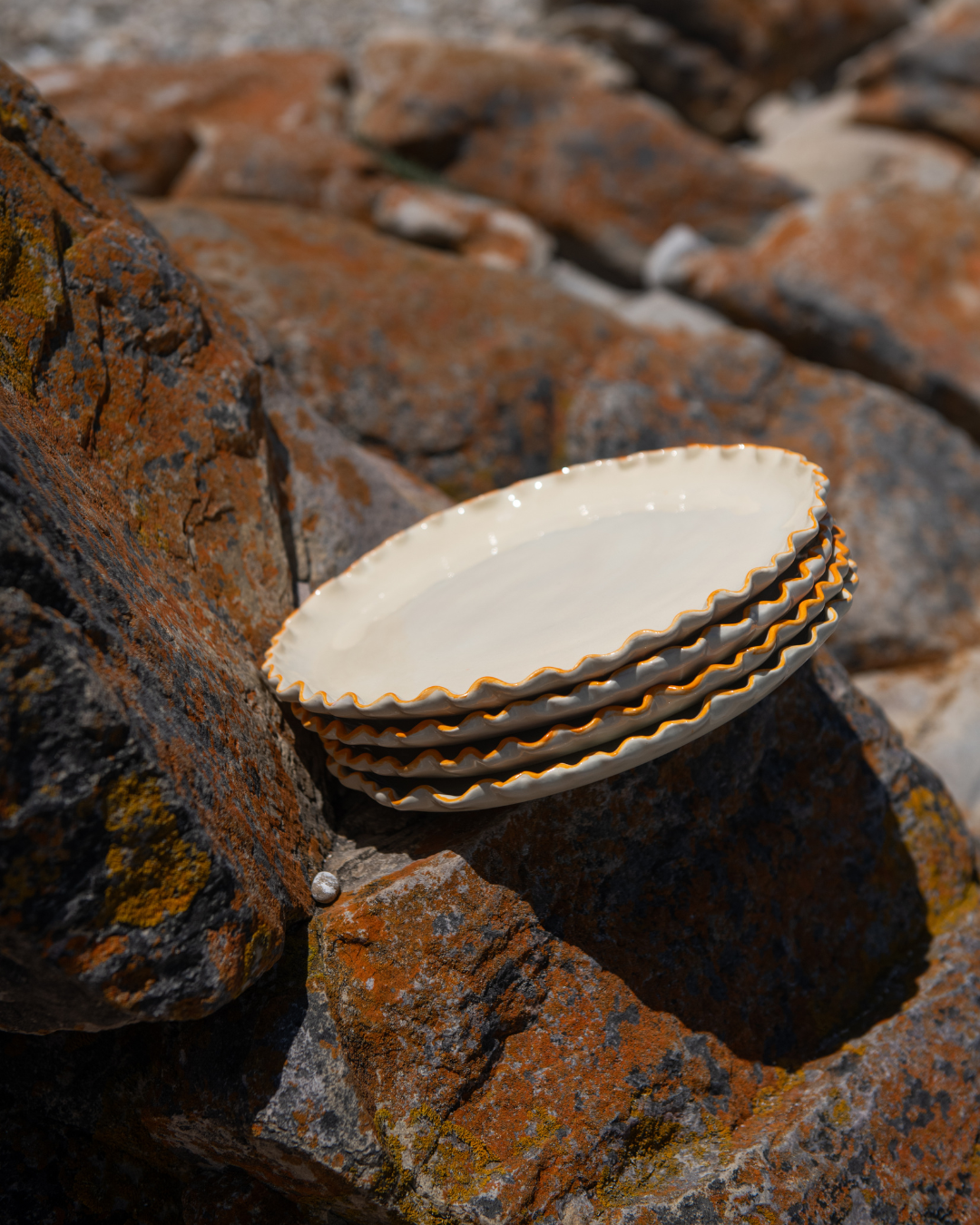 Stack of side plates with coral rim accents on a textured rock surface