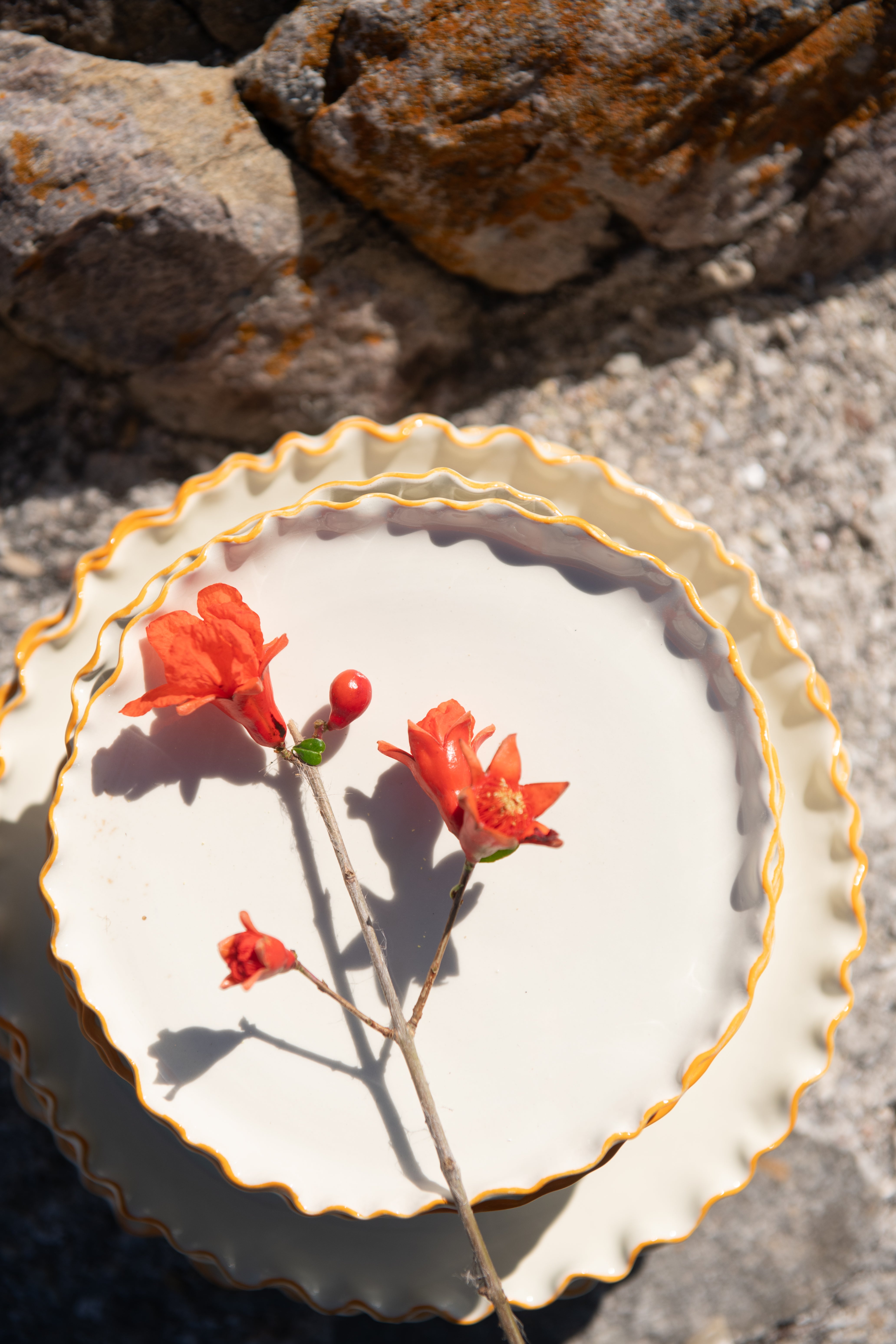 Stack of white plates with gold rims on a stone surface