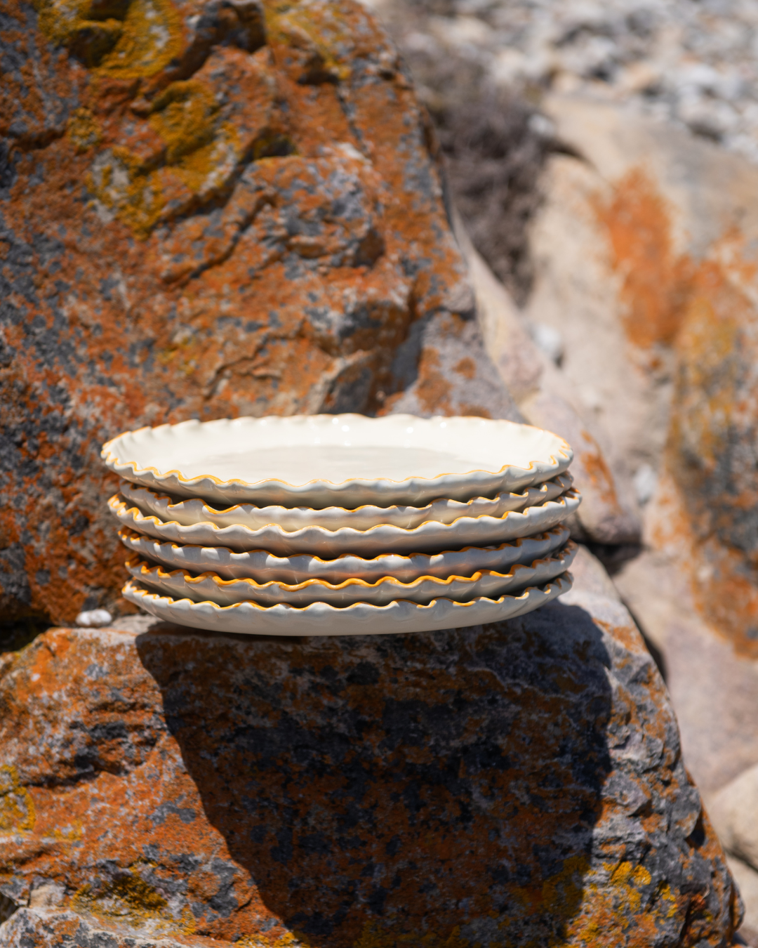 Stack of ceramic plates on a textured stone surface with lichen