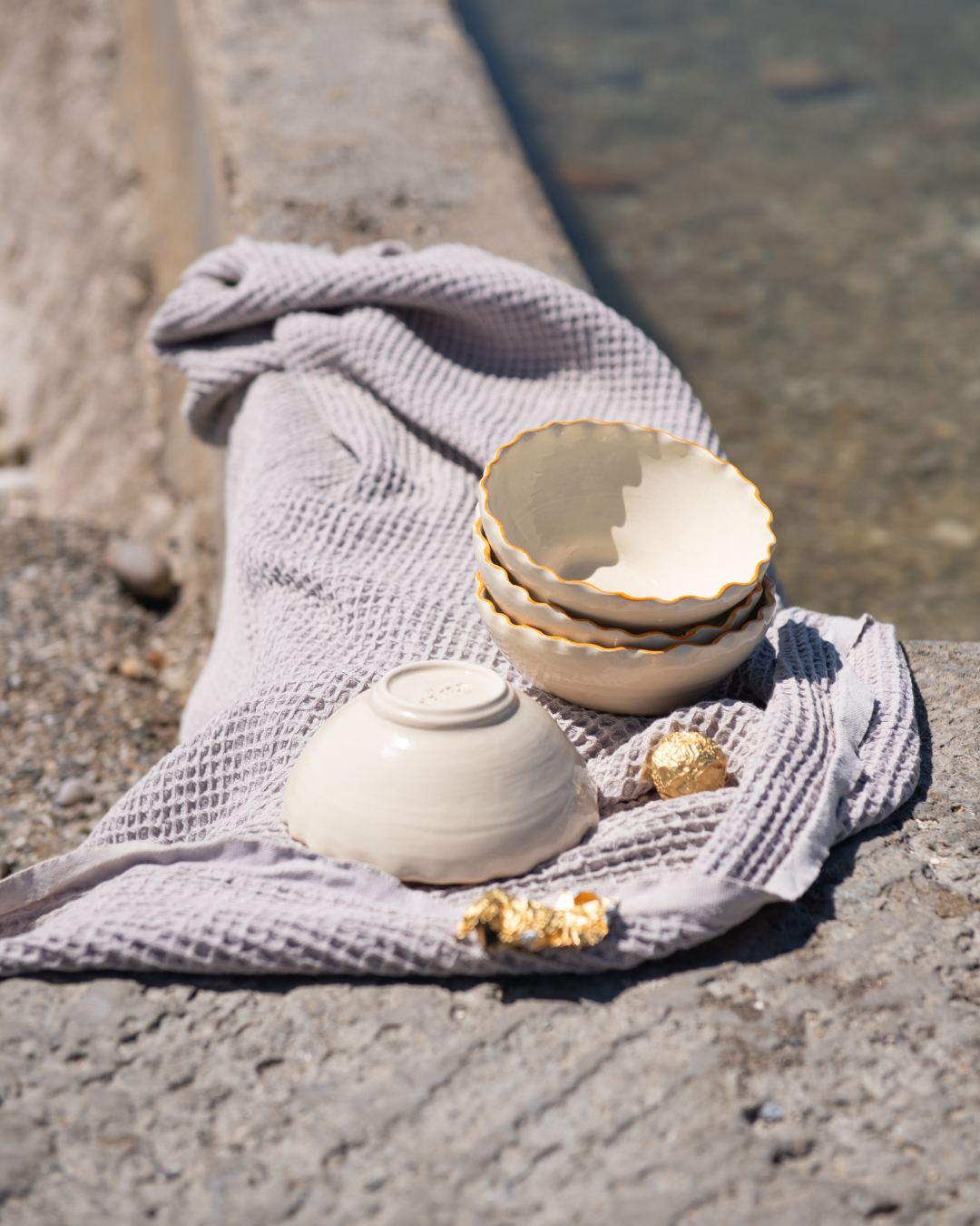 Stack of ceramic bowls on a textured surface with a towel and gold object.