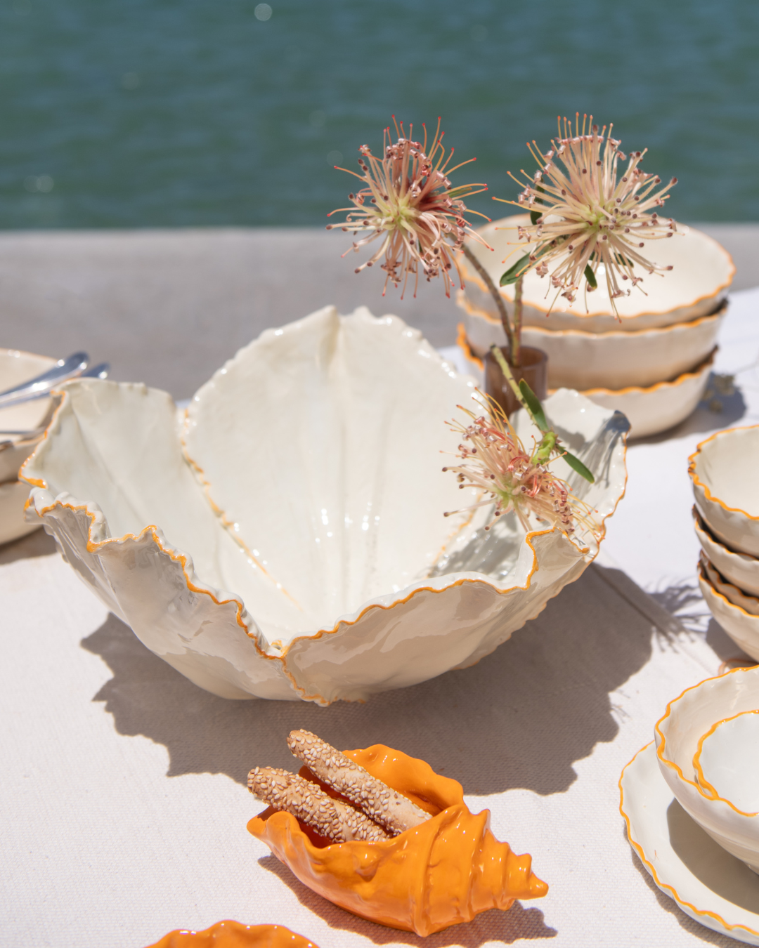 Decorative ceramic bowls with floral elements on a table by a body of water.