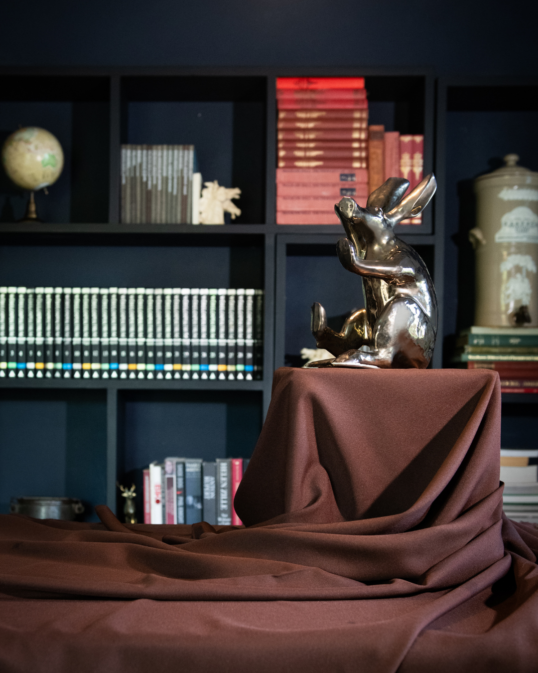 Aardvark statue of on a brown cloth with a bookshelf in the background