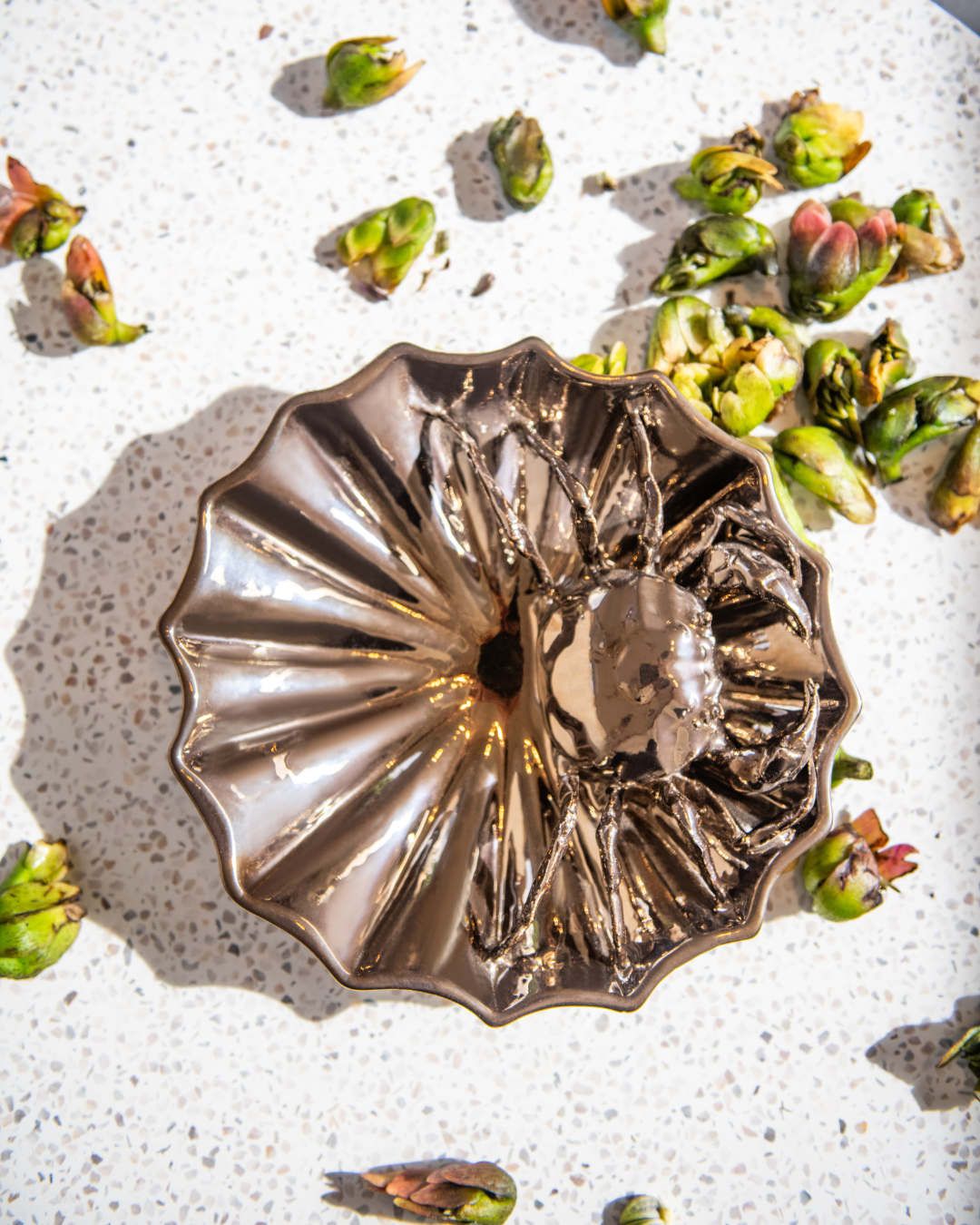 Decorative bronze ceramic Bowl  object with 3d crab inside the bowl on a textured surface with green buds.