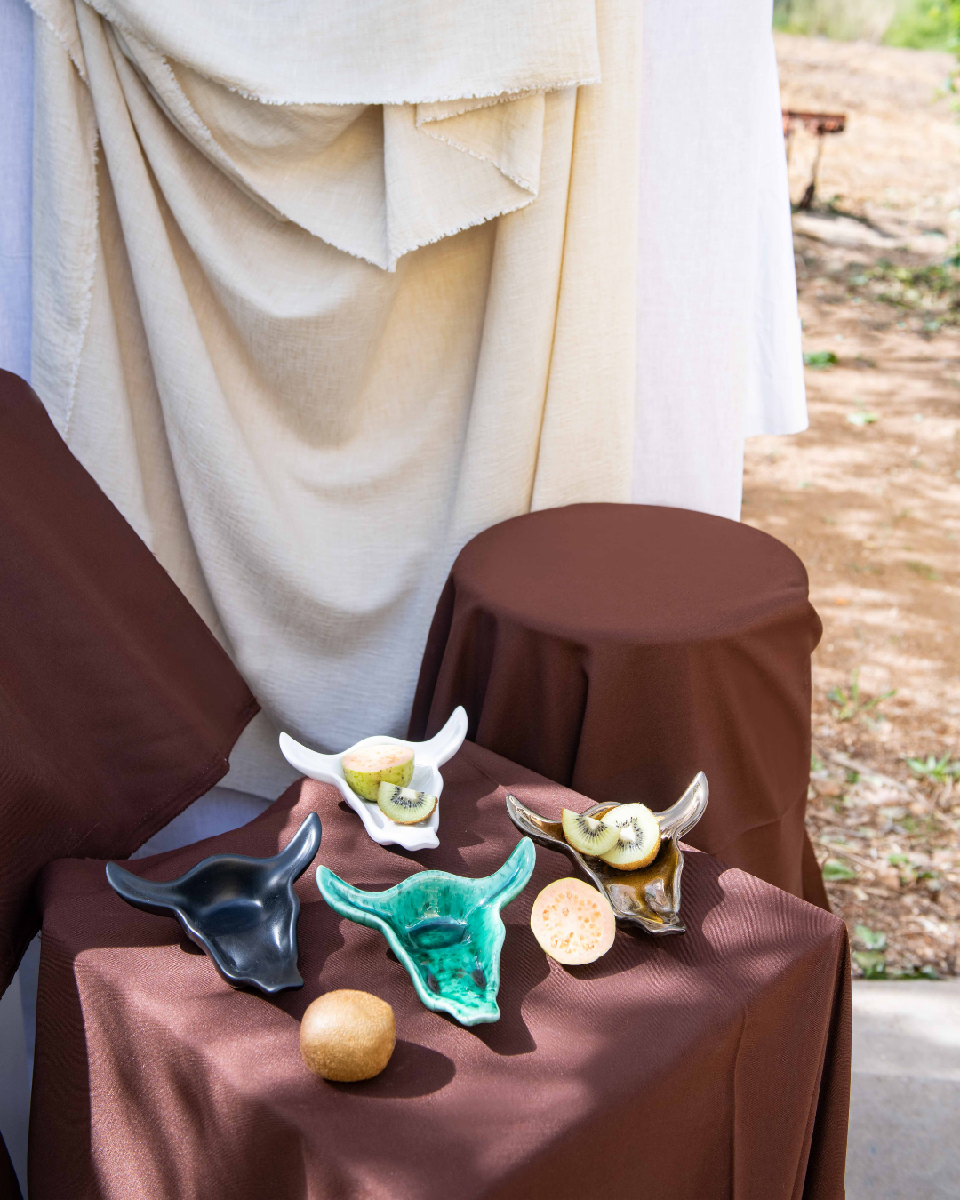 Decorative animal head sculptures on a brown tablecloth with a draped white cloth in the background.
