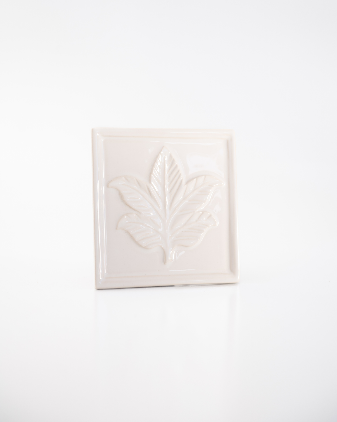 White ceramic tile with leaf design on a white background