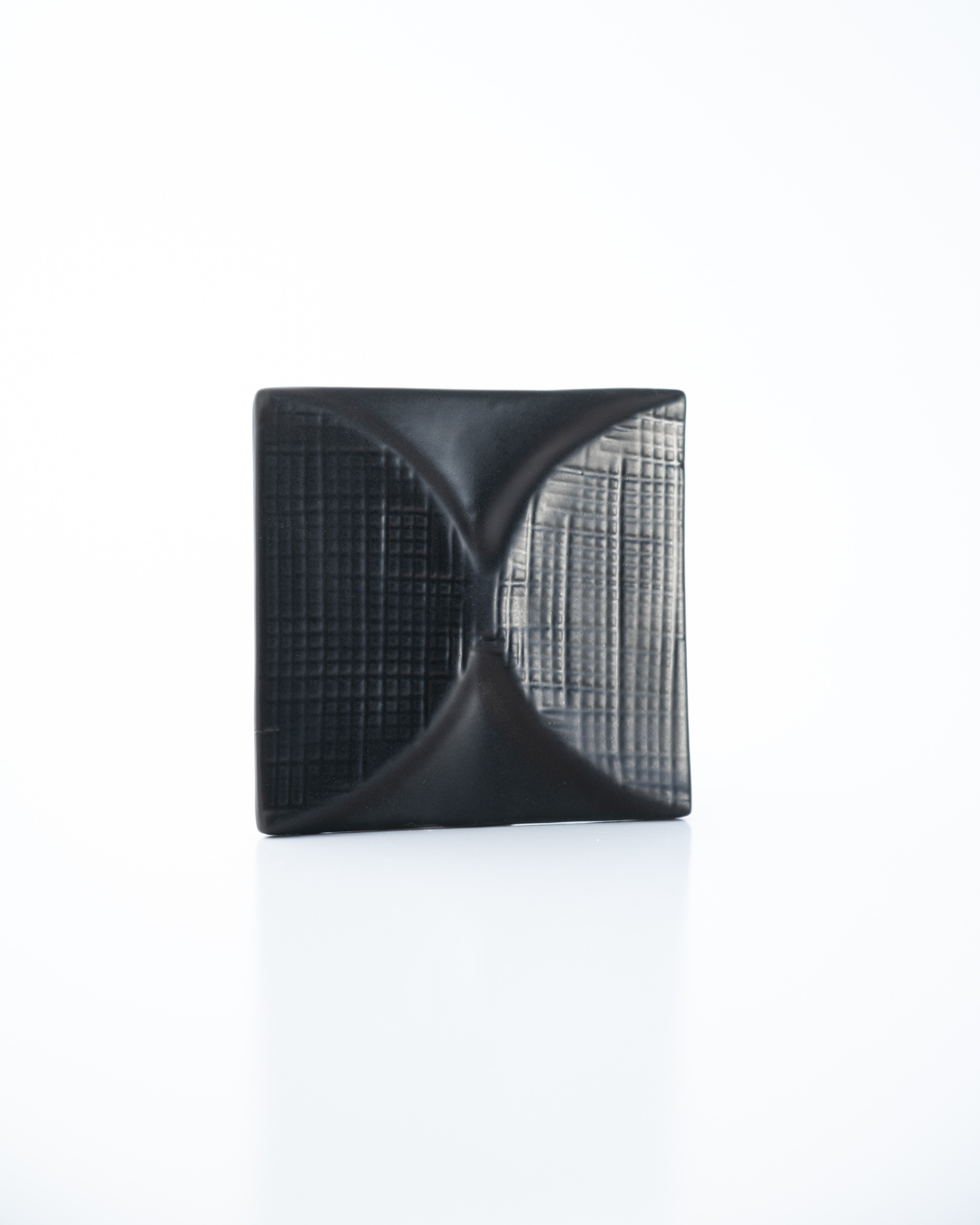 Black square ceramic tile with textured surface on a white background