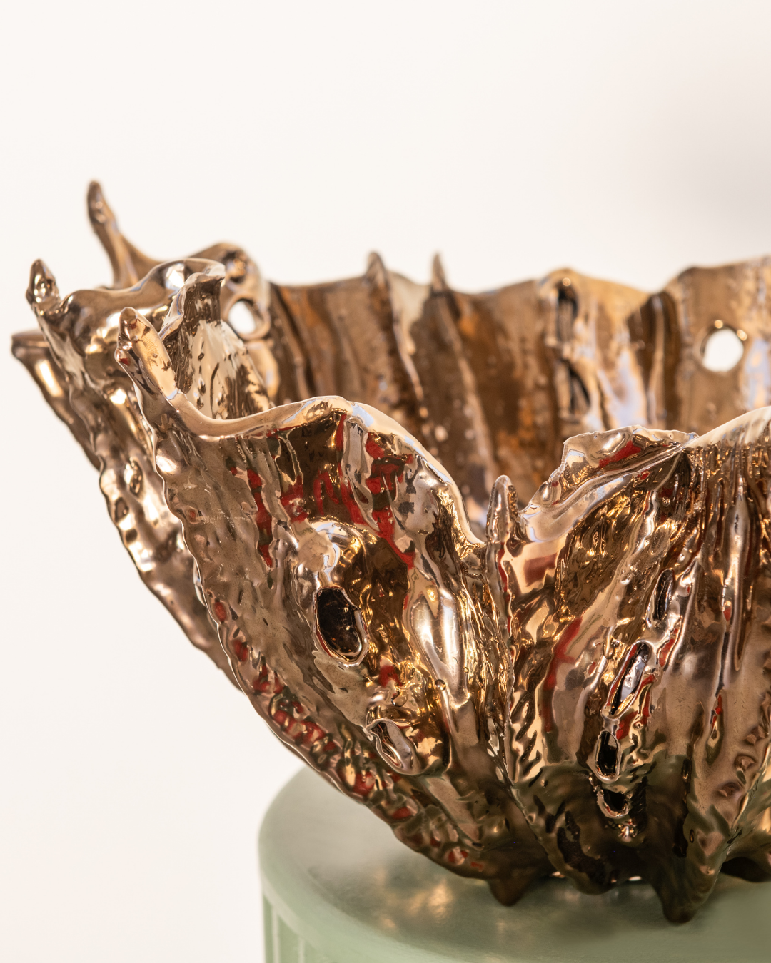 Bronze or copper-colored decorative bowl with wavy design on a white background