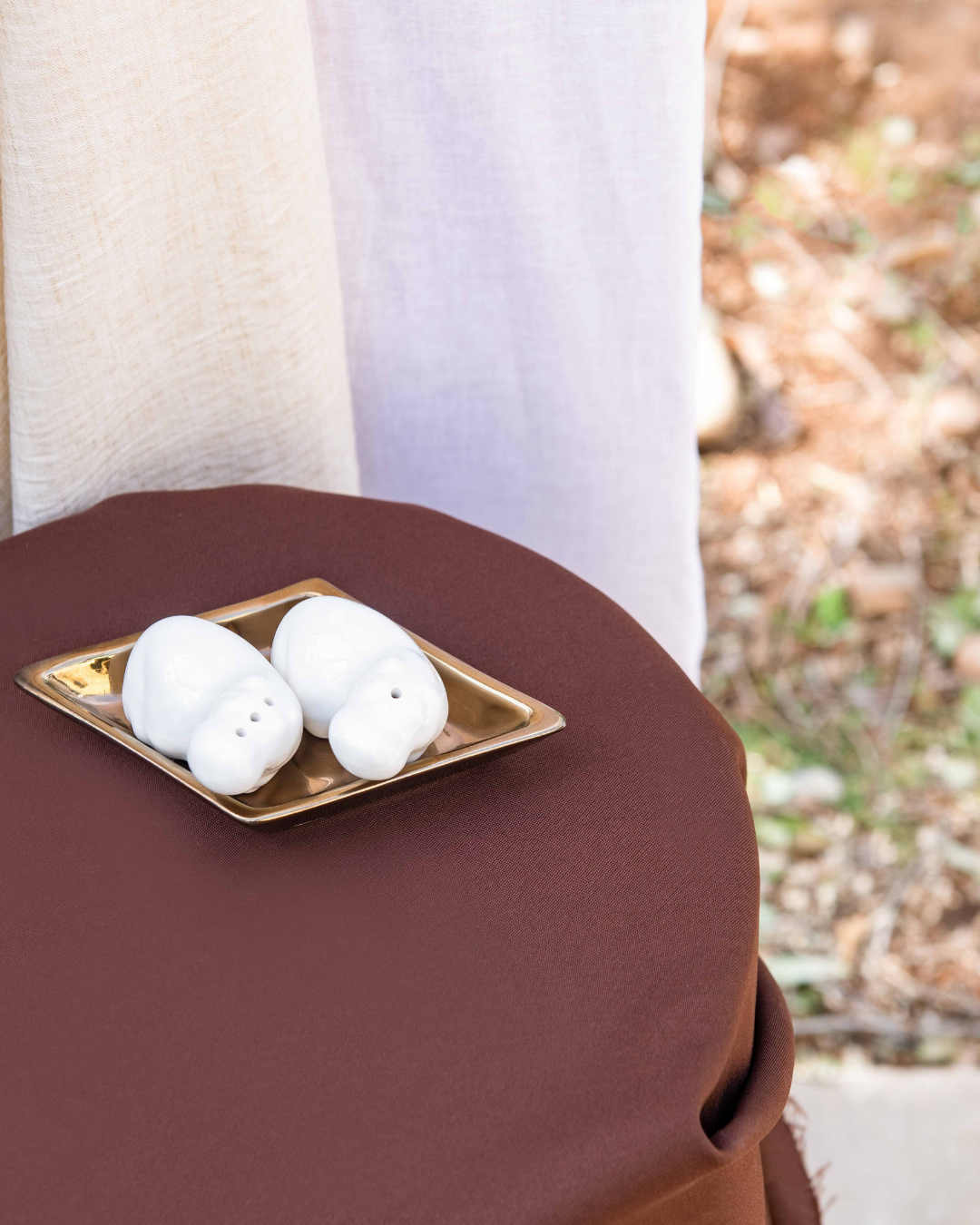 Two White ceramic hippos with holes for salt and pepper on a diamond shaped bronze ceramic tray