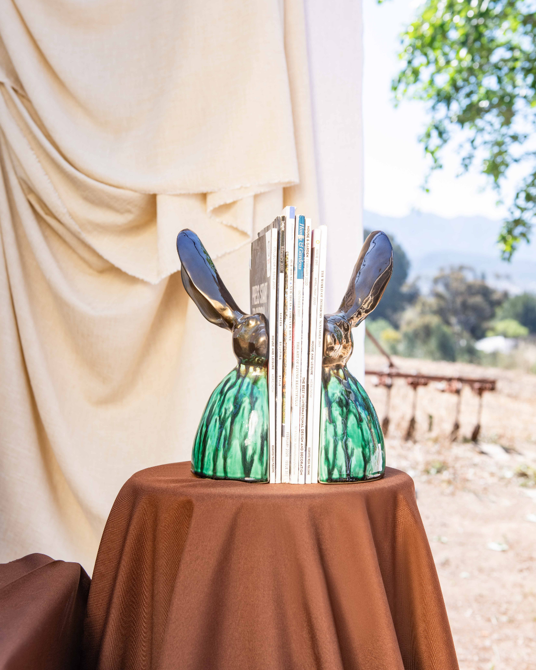 Decorative bookends shaped like rabbit heads on a table with a scenic background
