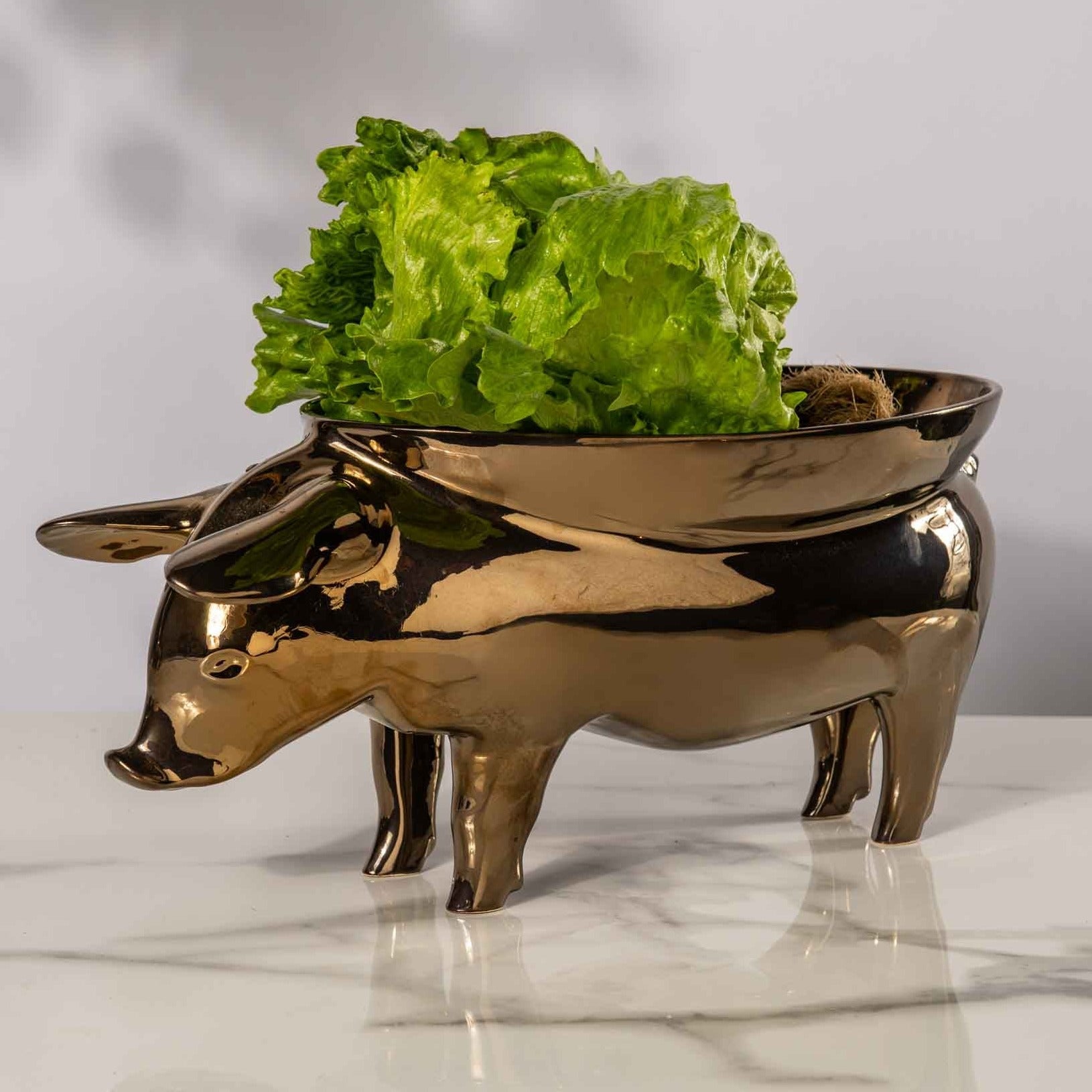 A white ceramic fruit bowl shaped like a pig, with intricate details and a curved body, perfect for displaying fresh fruit or using as a unique centerpiece in any kitchen or dining room.