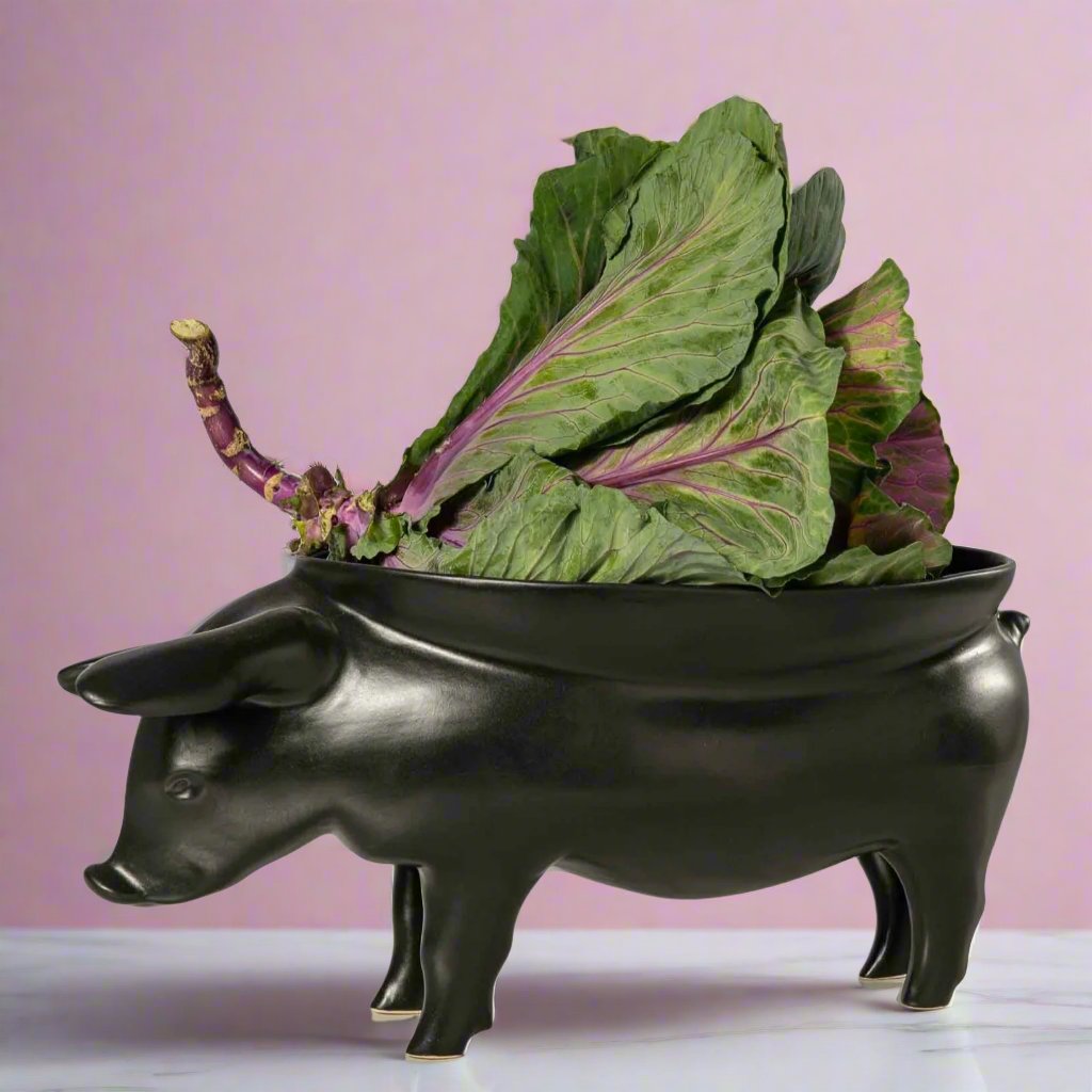 A white ceramic fruit bowl shaped like a pig, with intricate details and a curved body, perfect for displaying fresh fruit or using as a unique centerpiece in any kitchen or dining room.