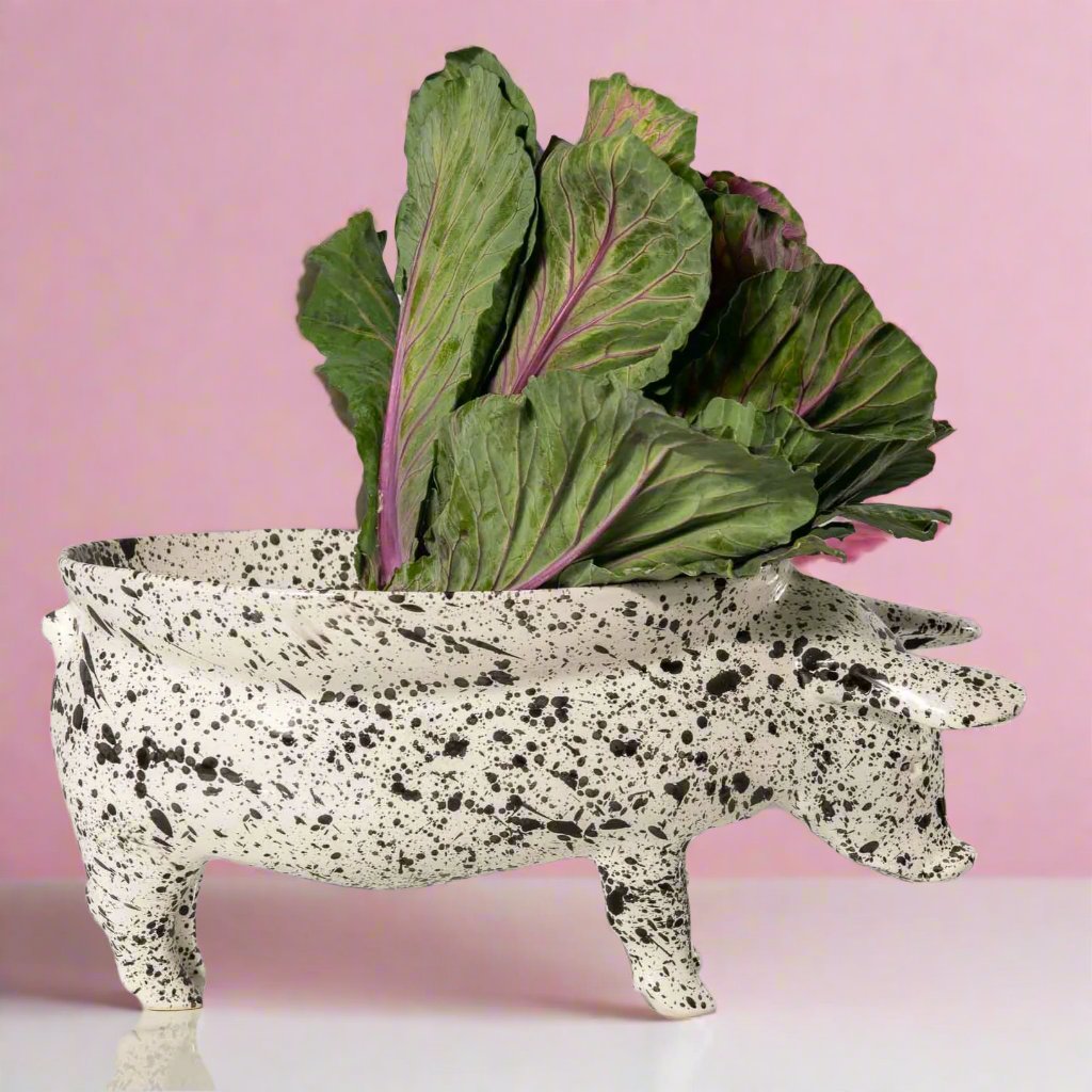 A white ceramic fruit bowl shaped like a pig, with intricate details and a curved body, perfect for displaying fresh fruit or using as a unique centerpiece in any kitchen or dining room.